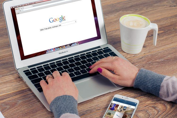 uma mulher sentada em frente a um computador com uma xícara de café ao lado e o navegador do Google aberto